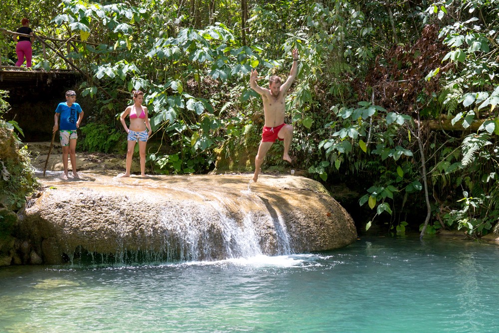 Jump into adventure and fun! Swimming Holes Image: A group of travellers stands at a swimming hole; one is poised to jump in.