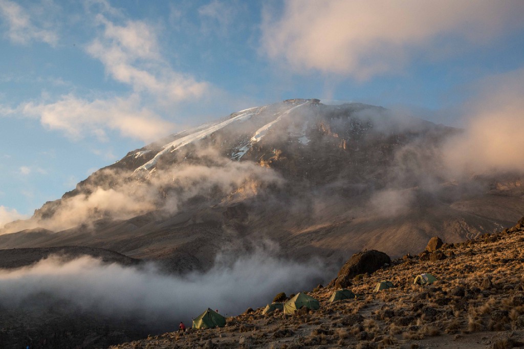 What a way to begin your morning. Destinations Worth Dreaming Image: Morning mist is beginning to burn off as the sun rises on a mountain. Green tents dot the landscape.