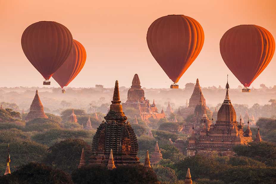 Well, this is certainly a memorable way to take in the Myanmar skyline. Destinations Worth Dreaming Image: Four rust coloured hot-air balloons float past the Myanmar skyline.