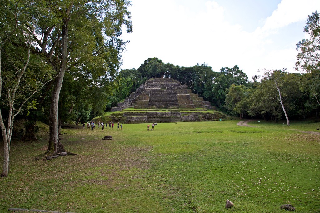 Observe how small everyone looks compared to this structure and the surrounding structure. Central and South American Ruins Image: A group of people is dwarfed by a pyramidical structure in the background, and the surrounding forest.