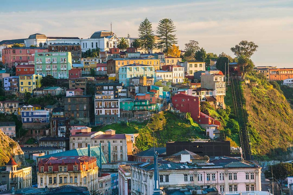 Colourful buildings make for an interesting city view. Destinations Worth Dreaming Image: Cubes of colourful buildings are present on a city hillside—the occasional green space or tree is present.