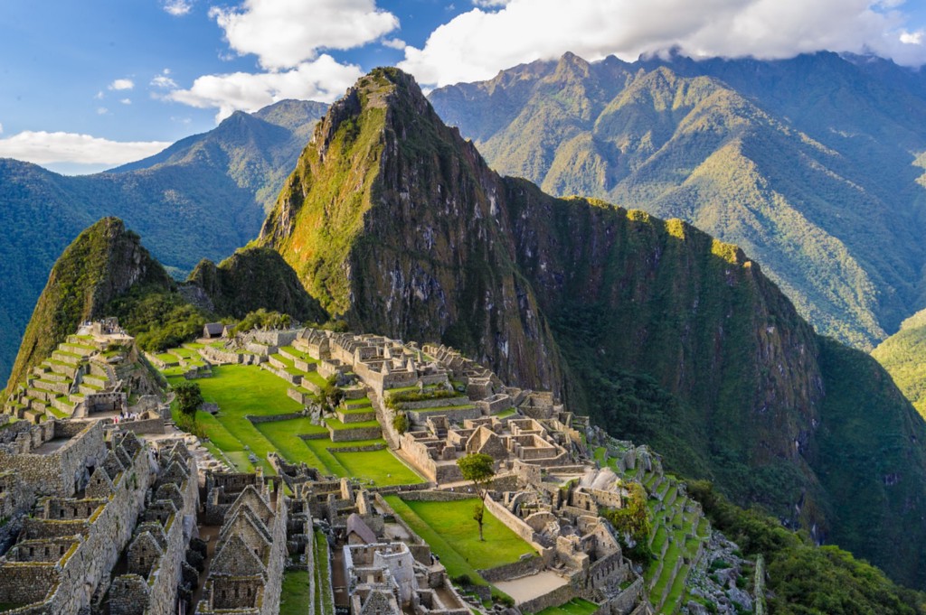 That caption was an altitude joke! Central and South American Ruins Image: A beautiful view of Machu Picchu reveals this Central and South American ruin to be a vision of green and brown mountains, a grey aged village, and a blue sky dappled with white clouds.