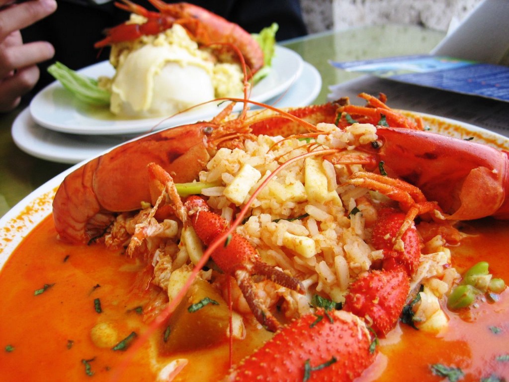 ...and the rice soaks up all of that delicious broth. Visit Peru Image: The vibrant red seafood soup is piled onto a white dish; a generous scoop of rice has been placed in the middle of the dish.