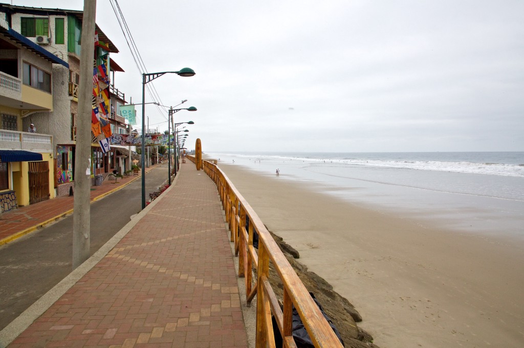 Seriously? The beach is right there! Best Surfing Beaches: Photograph of the city being divided from the nearby beach with a wooden railing and large stones.