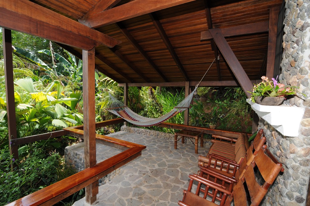 #Delightful Eco-Friendly Costa Rica Image: A stony veranda has chairs, and a hammock in the corner which looks like a lovely place to read a book or take a nap.