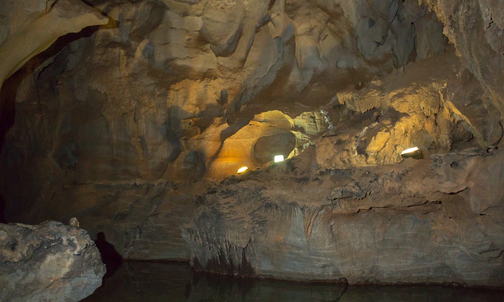 We're guessing that lighting probably wasn't original to the cave... Cave Floating Image: A photograph showing a lightly lit rock wall caressed by ebbing water in Cuba's Indian Cave.