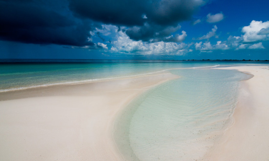 Whether the skies are cloudy or sunny, the beaches of Cuba are stunning. Are Cuba's Beaches Nice Image: A vibrant beach with clear waters, and a beautiful dark blue cloudy sky.