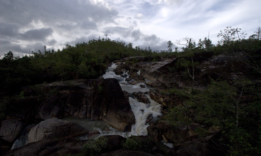 A far cry from Belize's tranquil beaches, Mountain Pine Ridge offers its own unique beauty. Belize River Tour Image: Winding water makes its way past trees and down the rocks of Mountain Pine.