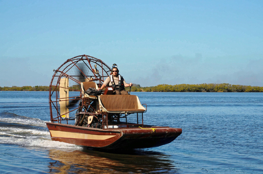 Jet across Belize in an airboat! Belize River Tour Image: An airboat rushes over the water.