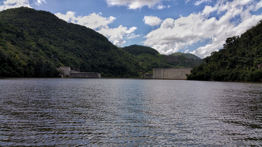 The pros and cons of dams are many. Do your research, and stay informed. Belize River Tour Image: A dam sits in the midst of a winding river flanked by jungle.