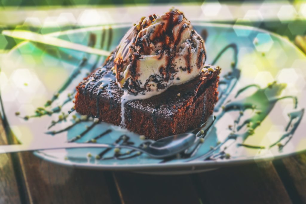 The only thing better than a brownie? A brownie with ice cream! Costa Rican Foods Image: A brownie sits on a plate, and is topped with a scoop of ice cream, and a chocolate drizzle.