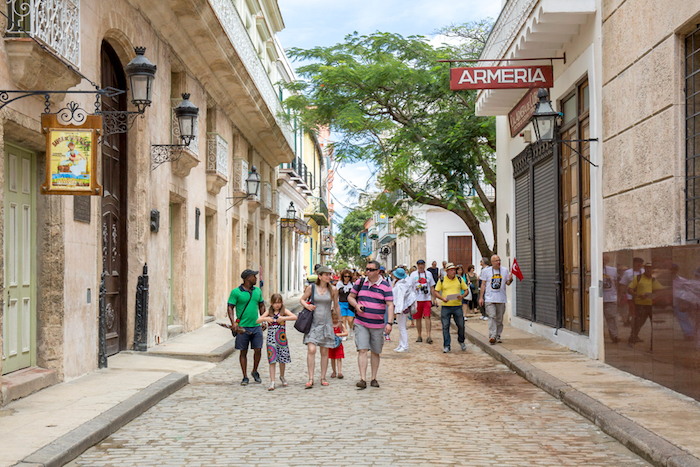 You're never too young to enjoy being a globetrotter. Family Vacations Image: A young family enjoys walking down a foreign street, sharing the sights with the children.