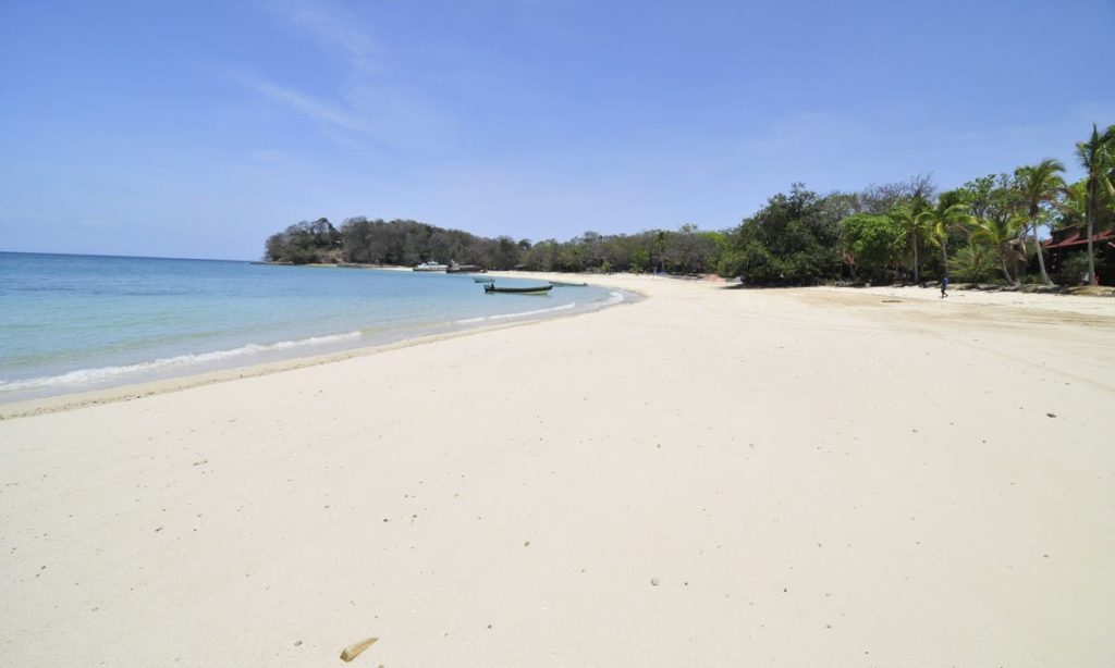 Having a beach to yourself is the ultimate beach vacation! Best Beaches Image: Panama. A beautiful but lonely beach has white sand, blue water and skies, and a boat near the shore. One person can be seen in the distance.