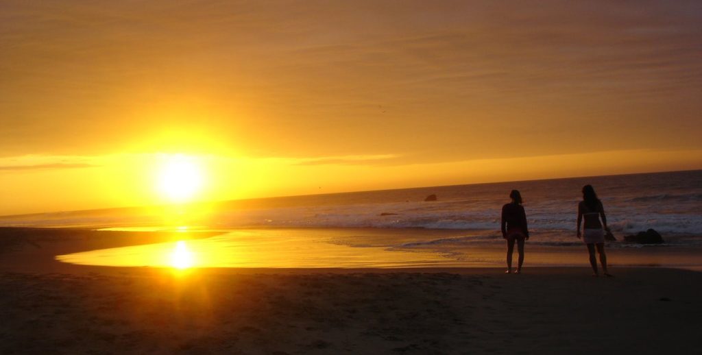 You too could be enjoying the sun setting over a Peruvian beach. Best Beaches Image: Peru. A golden sunset washes over a Peruvian beach as two onlookers take it all in.