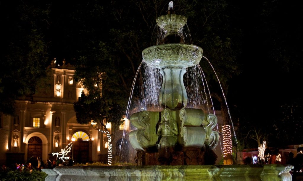 From ancient jungle ruins to city fountains—there is much for you to discover in Guatemala. Mayan Image: A fountain and possibly a Spanish-colonial building are illuminated on a dark night.