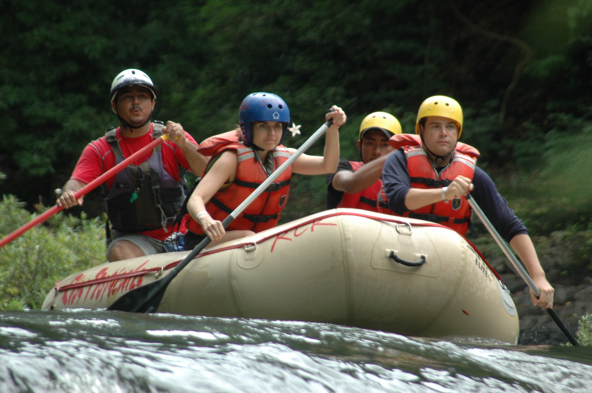 Navigating rapids is a fun but serious task. Costa Rica Rafting Image: Tenorio River. Four rafters with serious expressions concentrate on navigating the waters ahead of them.