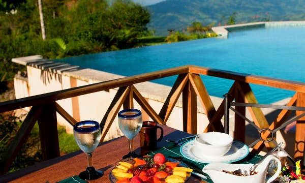 What a great way to start your day. Accessible Travel Image: A breakfast of tropical fruit overlooks a beautiful swimming pool, and a rainforest.
