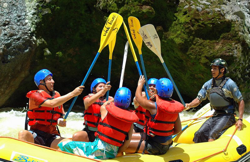 Celebrate your fun and adventure during your vacation. Costa Rica Adventure Trips Image: A group of five whitewater rafters and their instructor cheers their adventure by touching paddles.