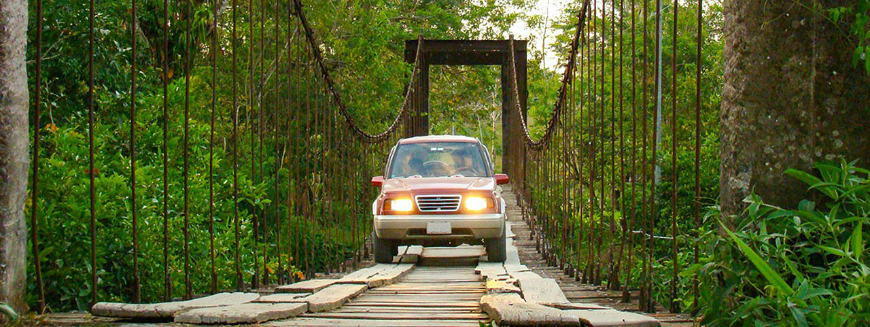 Just stay on the boards... Costa Rica Adventure Trips Image: A truck drives over a rope bridge laden with pieces of lumber for the wheels to drive over.