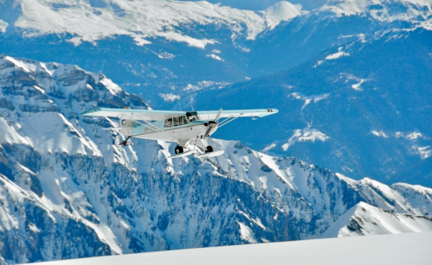 A small blue and white airplane is preparing to takeoff or land on a snow covered mountain. Altitude Sickness Image: A small blue and white airplane is preparing to takeoff or land on a snow covered mountain.