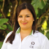 Sirleny is pictured wearing a white blouse. Her long brunette hair falls over one shoulder.