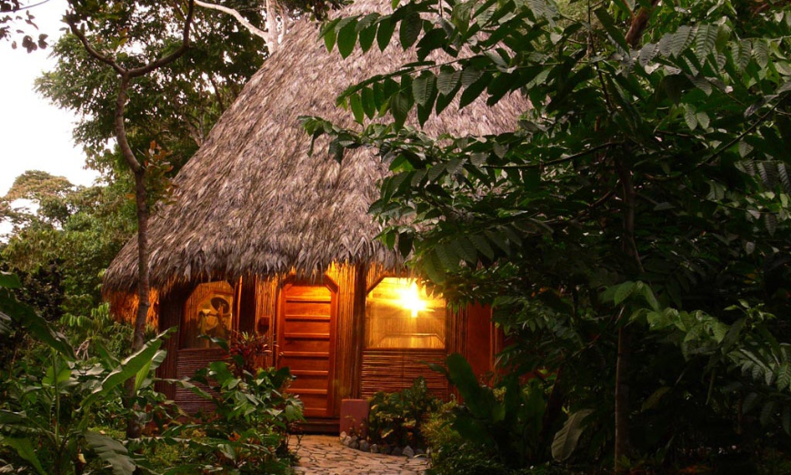 Don't just be adventurous in your choice of activities, be adventurous in your lodgings! Best Eoctourism Lodges Image: A light is shining through the window of a thatched roof bungalow.