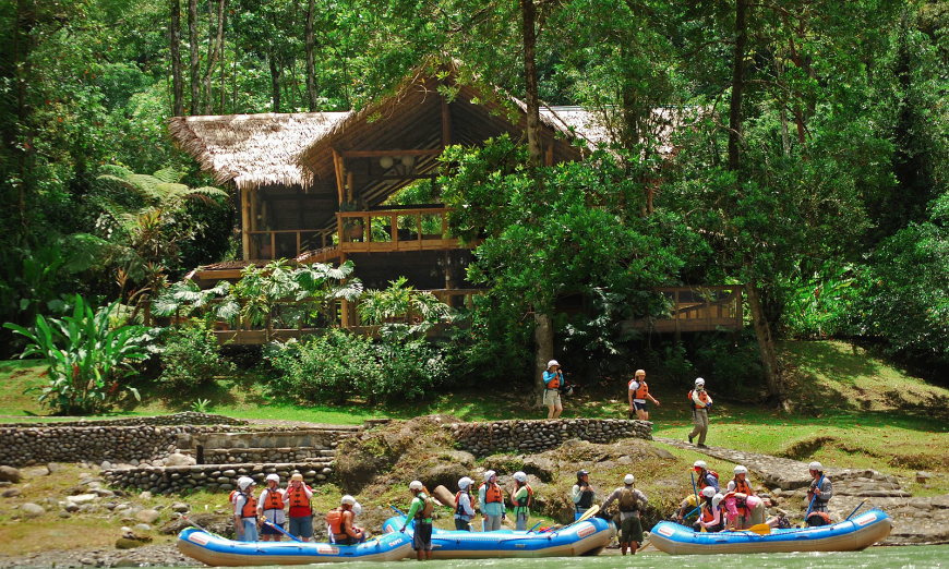 This group is clearly headed for a wild ride... Best Ecotourism Lodges Image: A group of white water rafters sit outside of a main lodge.