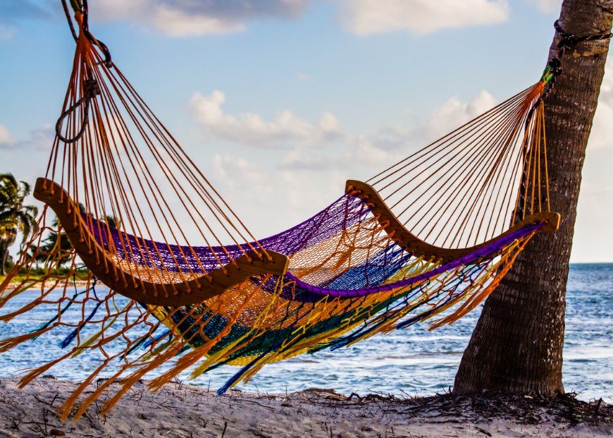 Best Islands in Belize for Couples Image: A colorful hammock sways in the breeze on a beach.