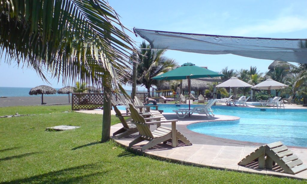 When you're on holiday, it's important to remember to treat oneself. Best Surfing Beaches: Pictured is the hotel's swimming pool, surrounded by lunge chairs, umbrellas, and palm trees. Outside of a wooden gate is an immaculate green lawn which leads down to the black sand beach.
