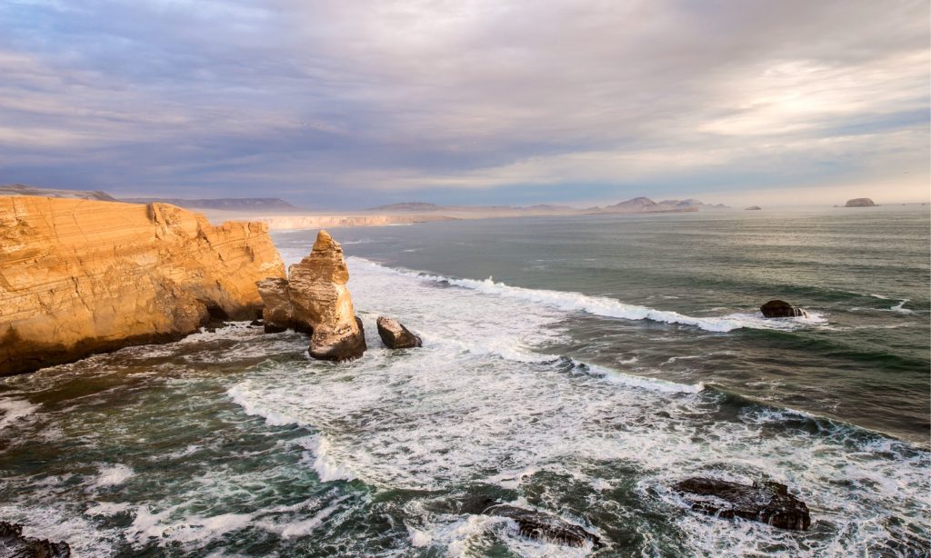 The Andean mountain range is beautiful, but so are Peru's beaches. Best Time To Visit South America Image: Peru's Cathedral Rock formation sits amidst ocean water.