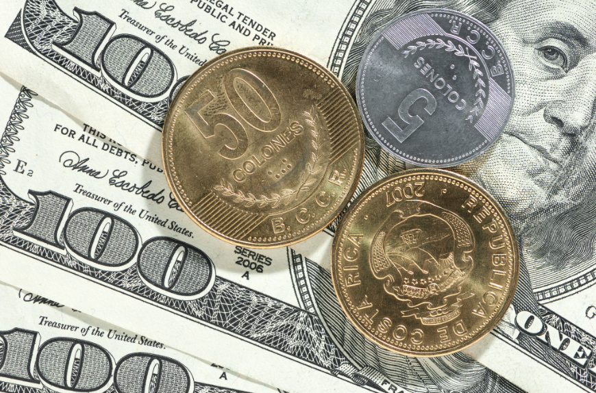 How is Katia able to offer advice about exchanging currency? Because, she actually LIVES in Costa Rica! Booking A Vacation Online Image: Three Costa Rican Colónes coins (two gold, one silver) sit atop three one hundred United States Dollar bills.