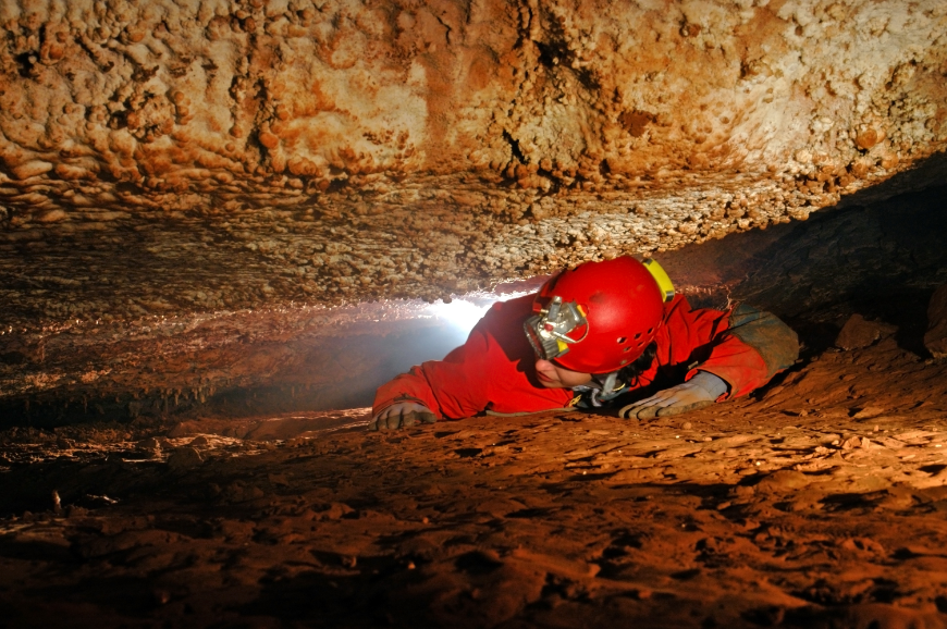 Not your idea of a good time? Thankfully, this is NOT the only way to explore a cave. Caving in Vietnam Image: An cave explorer crawls through a narrow passageway.