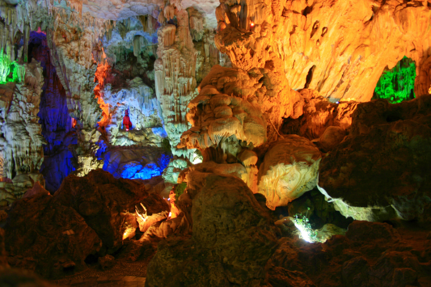 Who knew a cave could put on such a light show? Caving in Vietnam Image: Indigo, violet, orange, and green lights illuminate sections of Thien Cung cave.