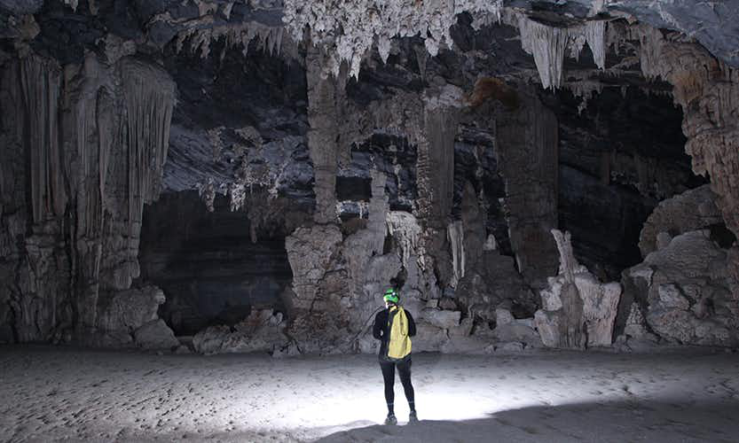 Caving in Vietnam Image: An adventurer observes the stalactites and other formations of the Tu Lan Cave System.