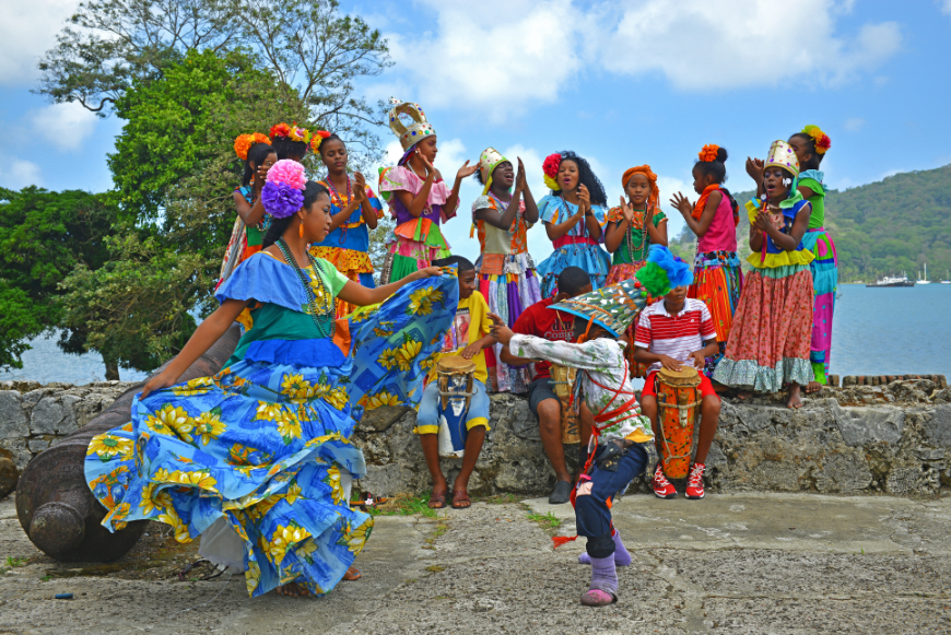 Dance in a sea of sunlight and color on your next vacation. Central America in Winter Image: A group of beautiful people dance in colorful dress under a sunny sky.