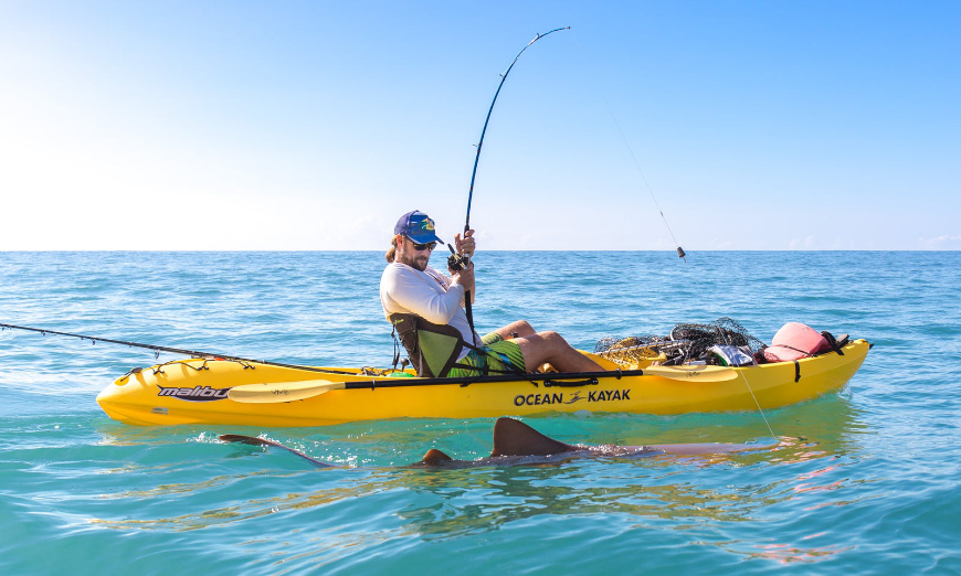 Sport fishing is another popular entry on the list of Costa Rica activities that make a great story. Costa Rica Activities Image: A man with a blue baseball cap sits in a yellow kayak sport fishing. He has caught a shark.