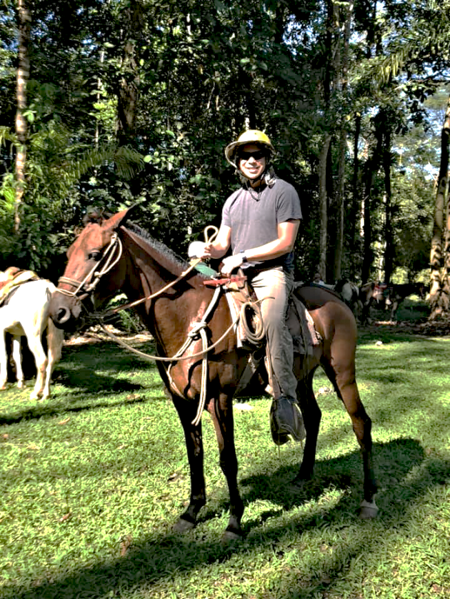 Costa Rica Couples Trip: Mr. Lepine on top of a brown horse, wearing sunglasses and smiling.