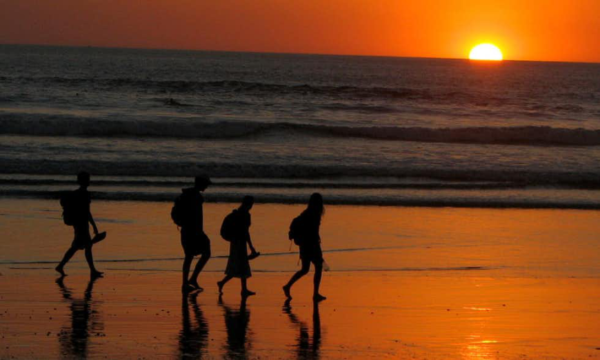 This beats messaging each other any day! Costa Rica Villa Image: Four people walk on a beach during sunset.