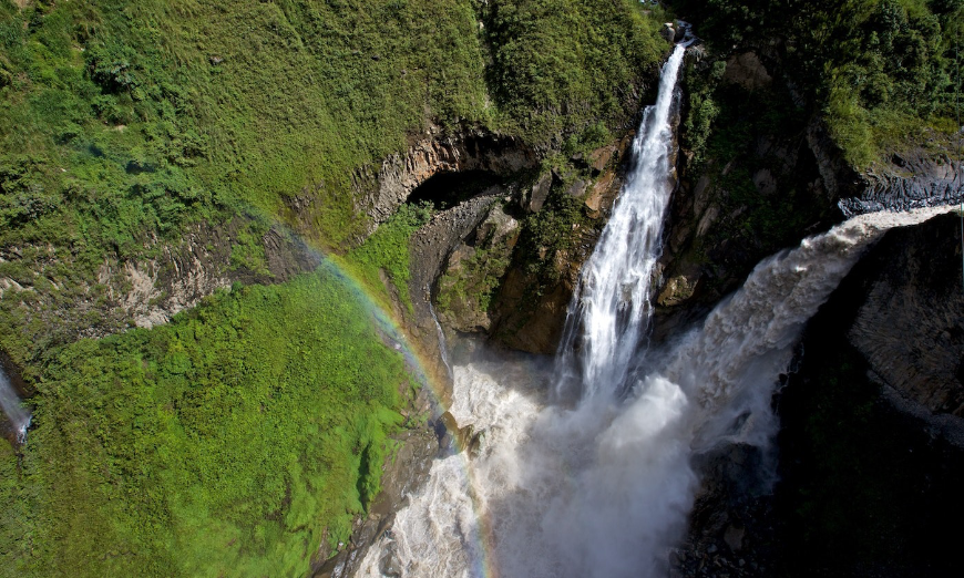 Take a break from wedding stress when you get some fresh air amidst the beauty of Ecuador. Destination Wedding in Ecuador Image: A rainbow crests over a green mountain with rushing waterfall and raging river.