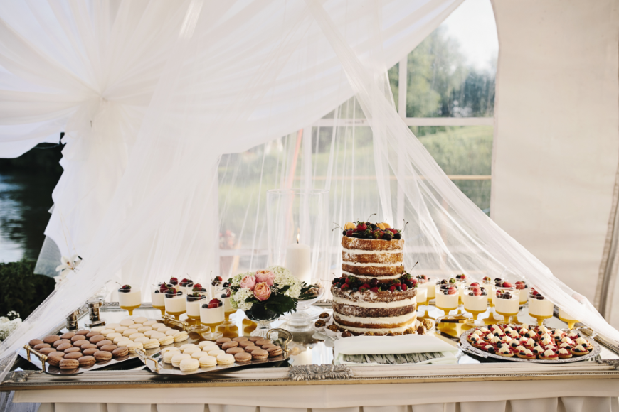 Bonus? In the event that someone doesn't like cake, everyone still gets a sweet treat. Destination Wedding in Ecuador Image: A dessert table has a wedding cake, cookies, parfaits, and more.