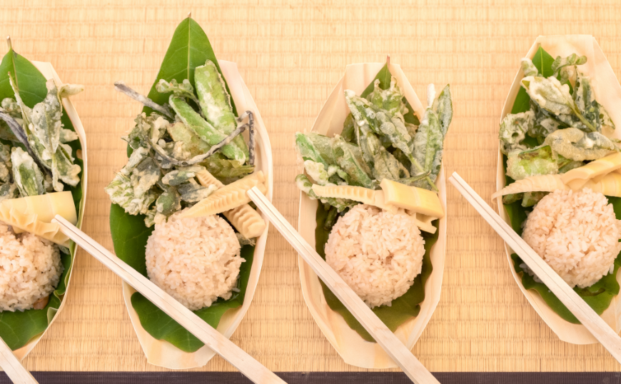 Make every part of your meal sustainable... Eco-Friendly Destination Wedding Image: A vegetarian meal including rice and vegetables rests on leaves in a natural container, served with chopsticks.