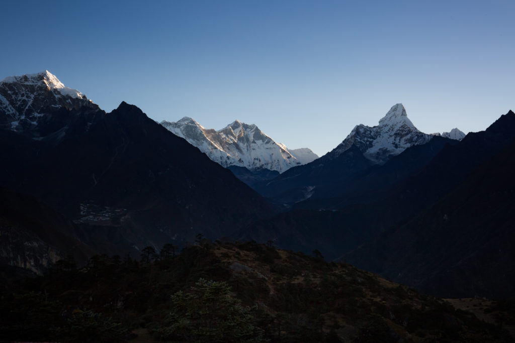 Mount Everest is both one of nature's most beautiful sights and most gruelling environments. Everest Base Camp Image: A view of snow capped mountains kissed by sunlight rising majestically from amidst smaller mountains in shades of green and brown.