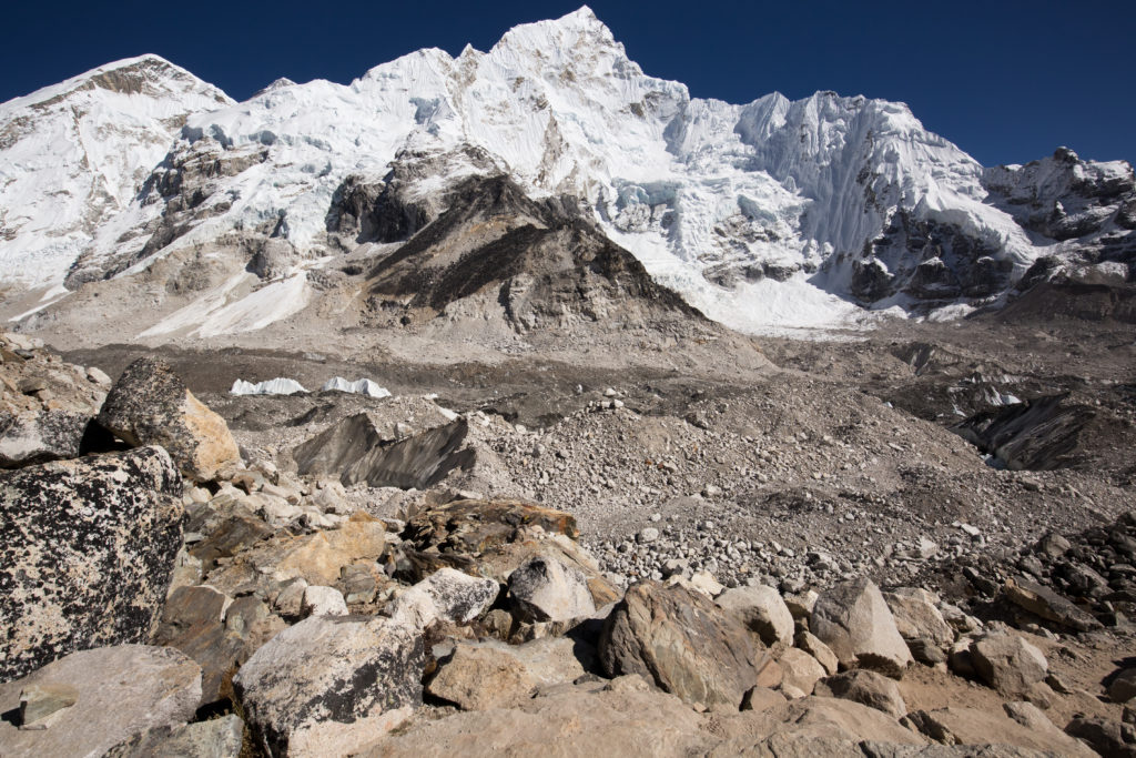 Need to get away for a while? On this trek, it's just you, your group, and the mountain. Everest Base Camp Image: From a rocky brown path, we see a larger snow covered peak.