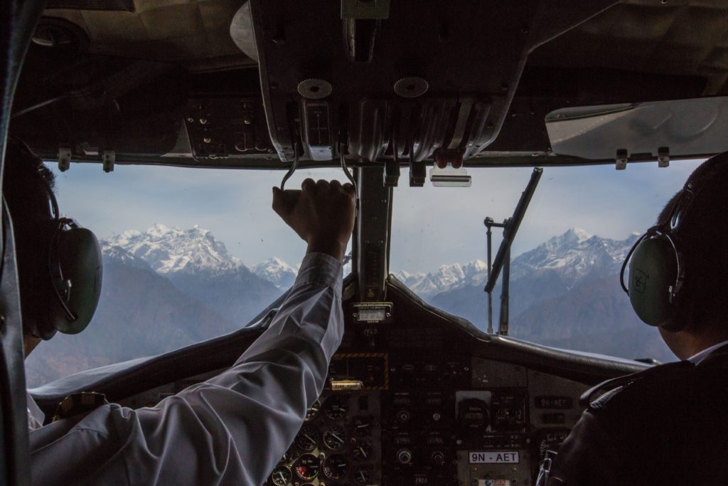 Prepare yourself... Everest Trek Image: The view from the cockpit of an airplane during the Everest Base Camp Trek. A pilot and co-pilot are off to the side navigating.