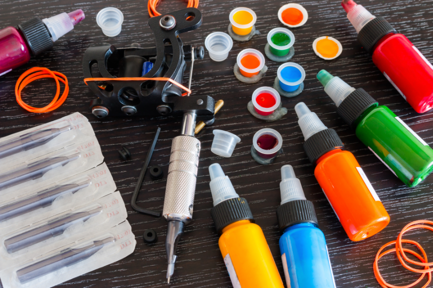 A different kind of palette and brush... Everest Tattoo Image: Tattoo supplies including paint pots and bottles, needles, and tattoo machine.