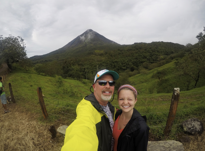 Costa Rica Green Season Adventure Image: Hayley Lewis and her father stop to pose for a photo with Arenal Volcano behind them.