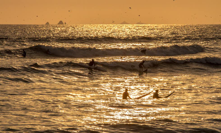 Join these surfers as they head toward a new adventure... Lima Nightlife Image: Surfers come in from waves as the sun sets on the ocean.