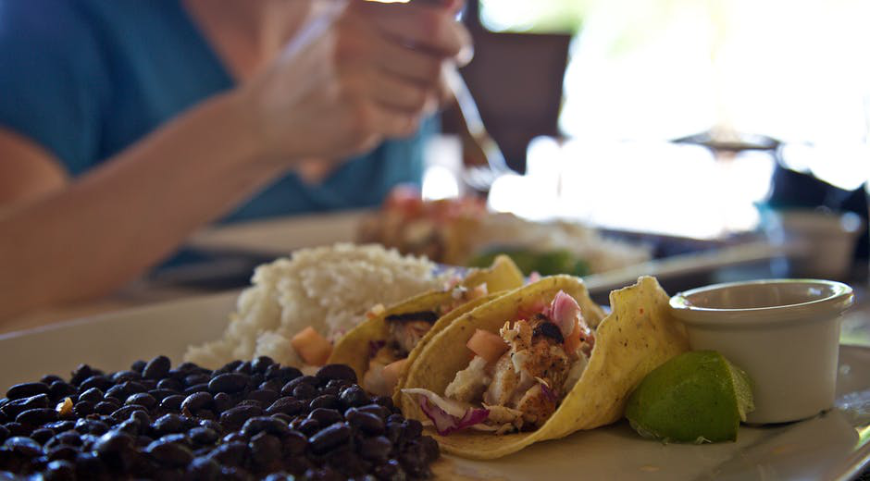 Generous servings of rice and beans, excellent seafood, and fresh fruits are waiting for you in Belize. Moving to Belize Image: Close-up of a hearty helping of black beans, rice, and tacos served with a lime wedge.