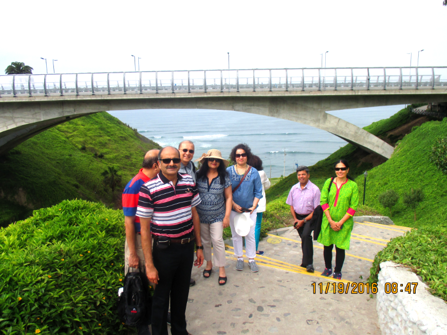Your friends and family will be more interested in your travel stories when they're a part of them. Peru Group Tour Image: A group photo in front of an ocean view.