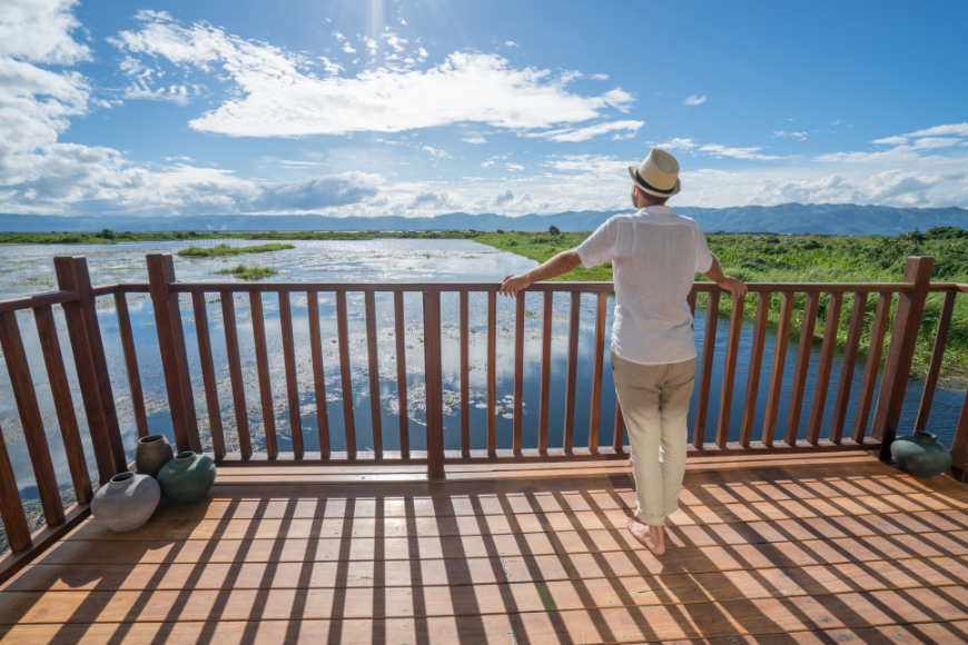 Moving abroad is like a marriage—you have to be prepared to love your new city in good times and bad. Retiring Abroad, Moving Abroad Image: A man stands on a blacony and overlooks water, sky, and land.